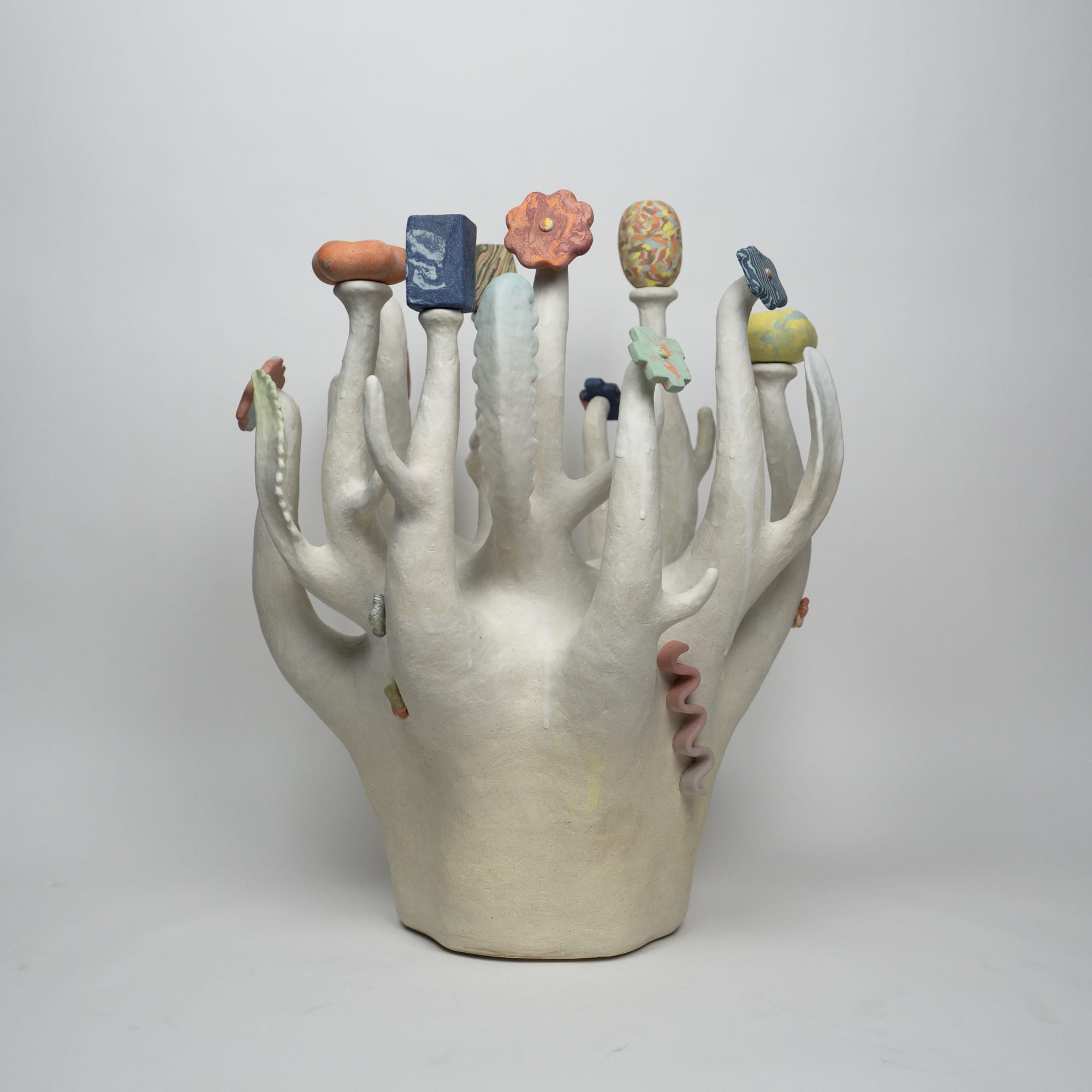a ceramic sculpture by Janny Baek with colorful organic forms emerging from white shoots