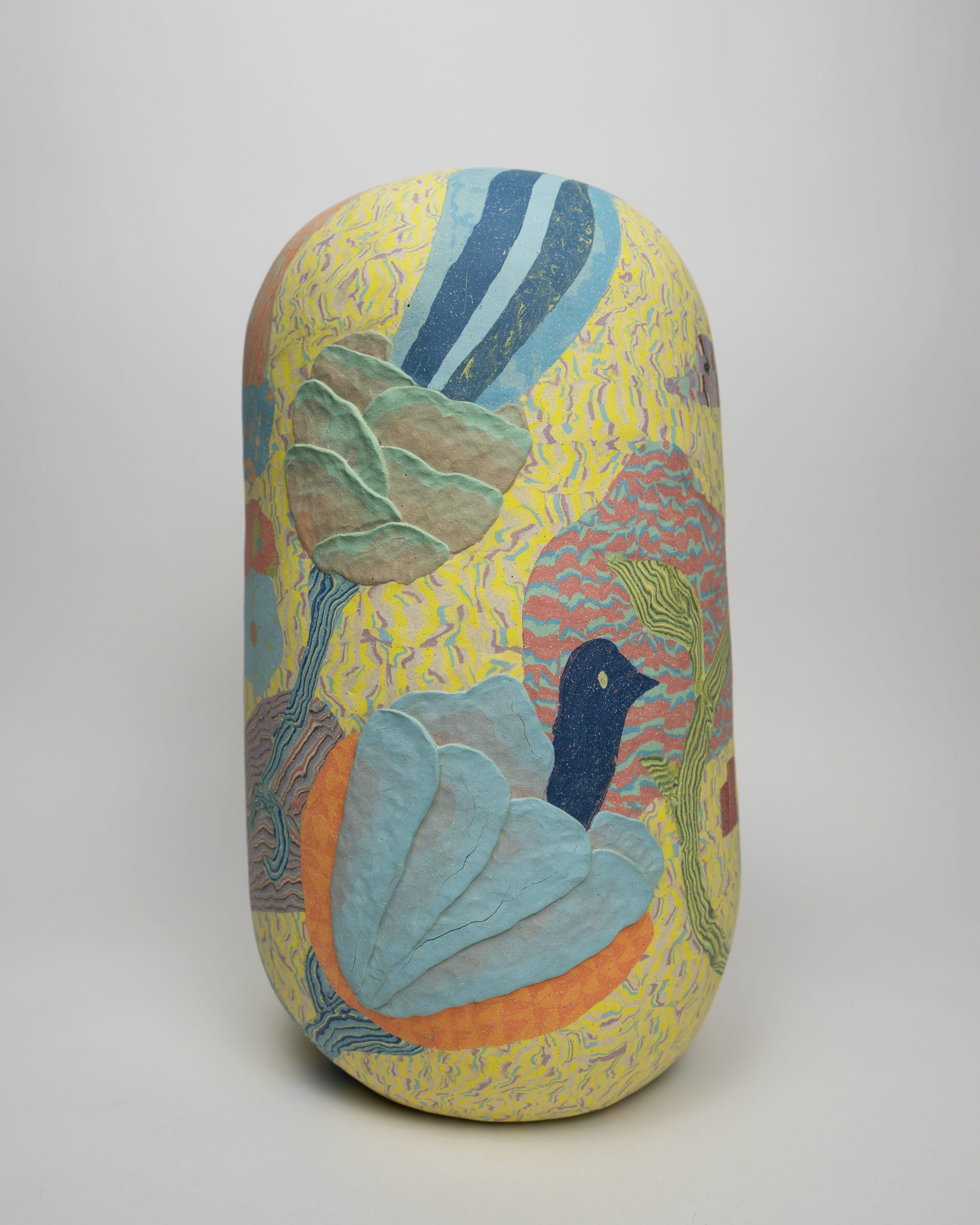 a ceramic sculpture by Janny Baek with patterned colorful clay and a blue bird form emerging from a lighter blue flower