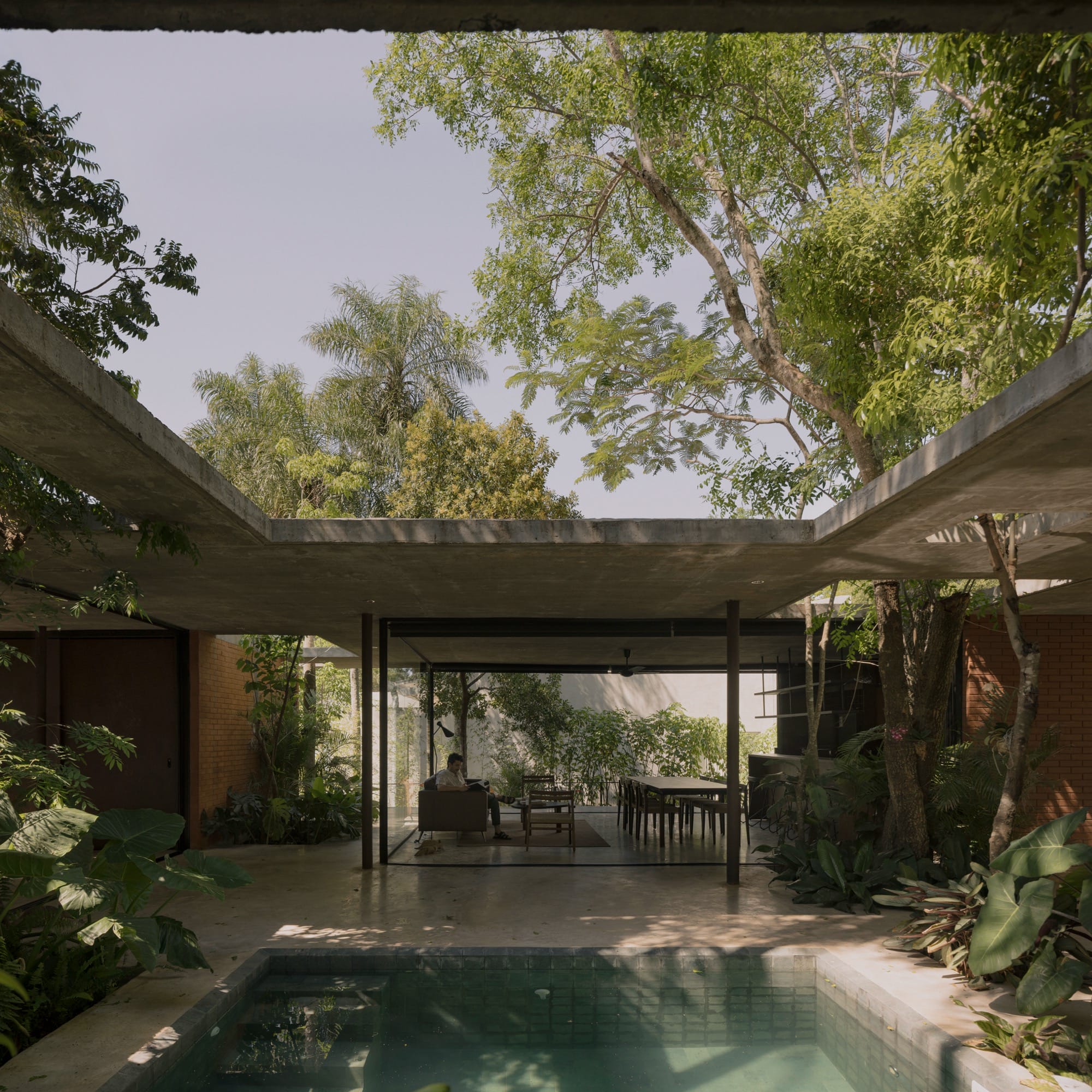 The inner courtyard of a contemporary concrete, glass, and steel home amid trees and tropical plants