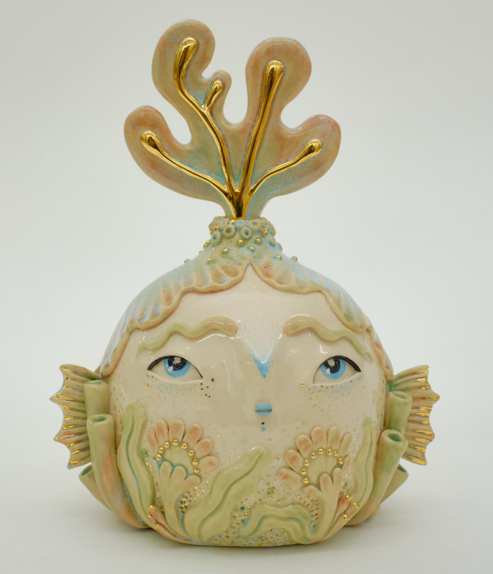 a ceramic sculpture by Abi Castillo of a head with fins as ears, coral details, and an anemone protruding from the top of its head