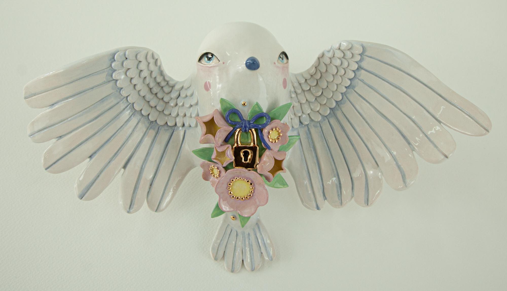 a ceramic sculpture by Abi Castillo of a white bird with a lock on its body, with floral and star-like pastel details