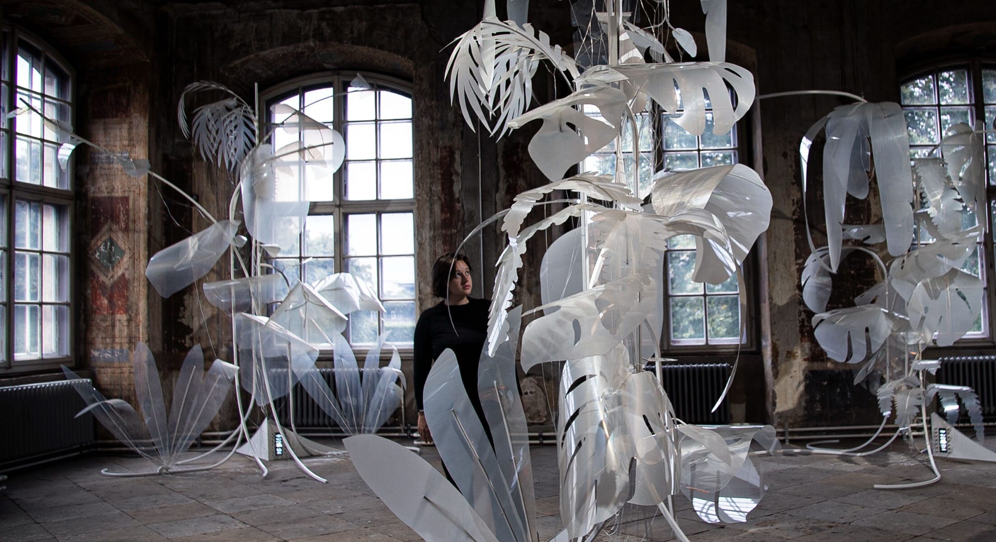 an installation view of sculptural, white tropical leaves 
