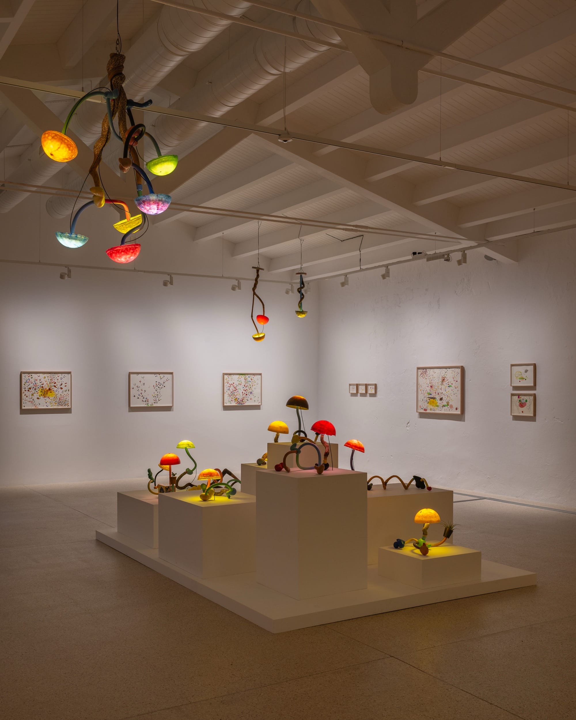 an installation of illuminated mushroom sculptures by Mika Rottenberg in a large white gallery space