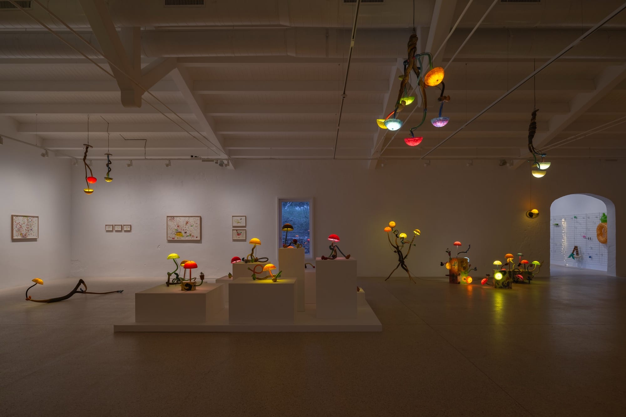 an installation of illuminated mushroom sculptures by Mika Rottenberg in a large white gallery space